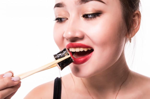 Close portrait of happy woman eating sushi roll avec des baguettes