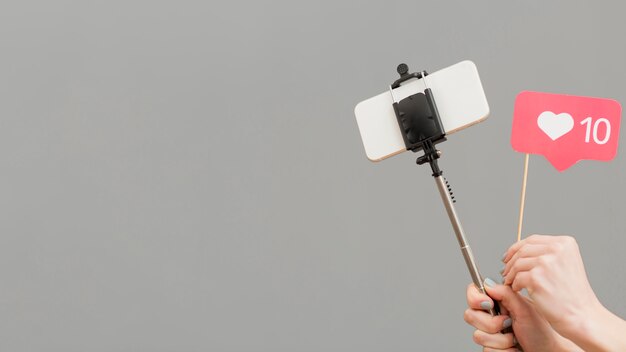 Close-up blogger holding selfie stick avec téléphone portable