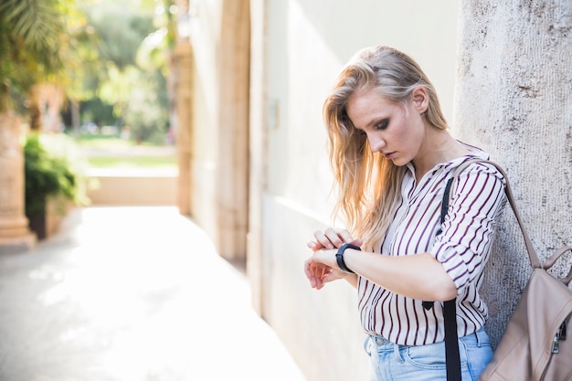 Close-up de blonde jeune femme vérifiant son temps sur la montre