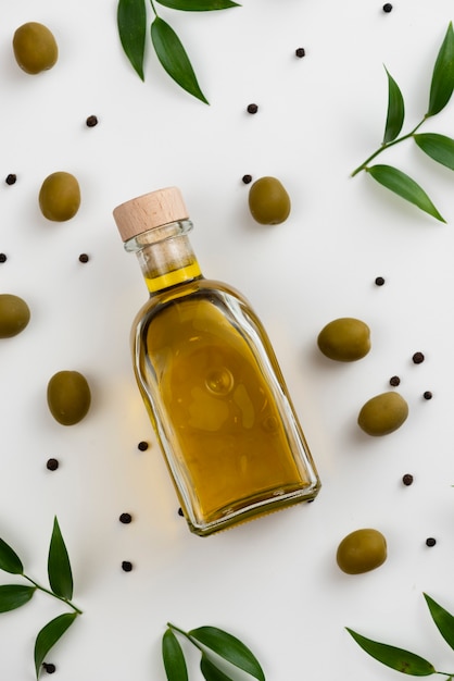 Photo gratuite close-up bouteille d'huile d'olive avec des feuilles suivant