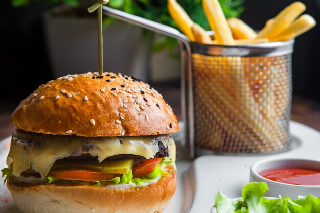 Close up cheeseburger cheeseburger fait de viande burger, fromage, tomate, laitue, oignon et concombre mariné avec pommes de terre frites et sauce sur table en bois