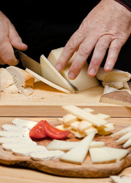 Close up chef coupe du fromage sur planche de bois
