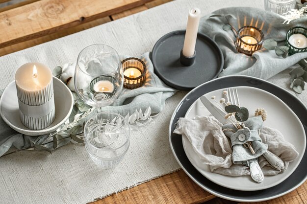 Close up detail d'une table de fête avec un ensemble de couverts, une assiette et des bougies en chandeliers.