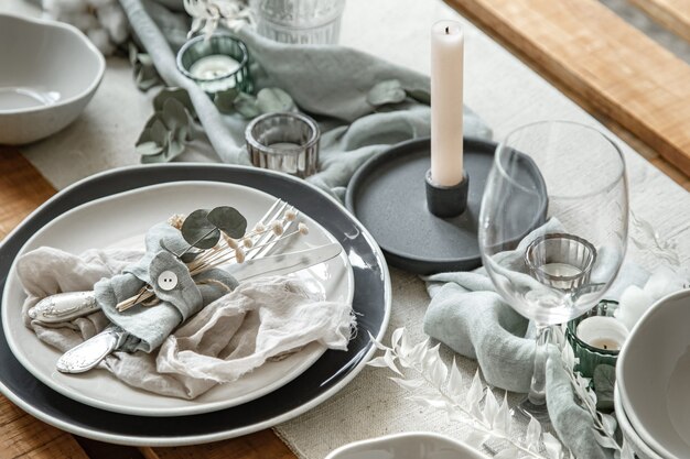 Close up detail d'une table de fête avec un ensemble de couverts, une assiette et des bougies en chandeliers.
