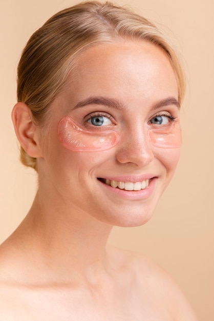 Close-up femme avec large sourire et tampons pour les yeux