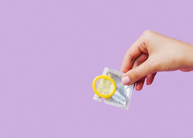 Close-up femme tenant un préservatif avec un espace copie