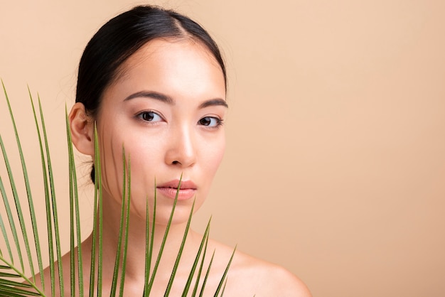 Close-up fille asiatique posant avec des feuilles