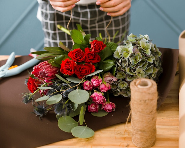 Close-up fleuriste utilisant du fil pour bouquet