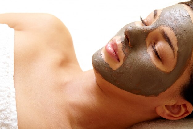 Close-up de la jeune femme avec un masque facial sur le visage