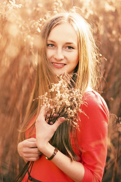 Close-up de la jeune femme avec une robe rouge tenant un bouquet