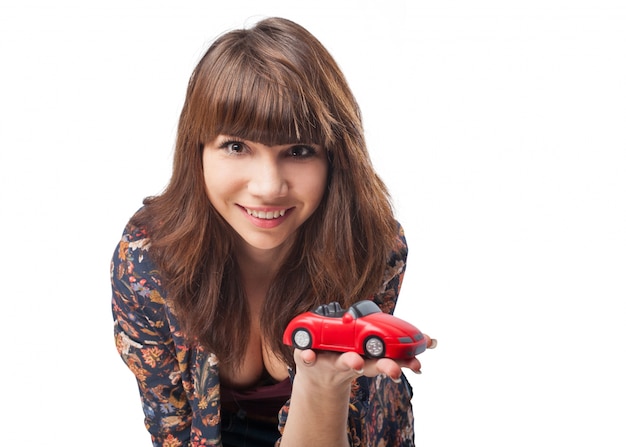 Close-up d&#39;une jeune fille souriante montrant une voiture jouet