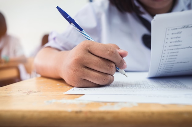 Close-up main d'étudiants écrivant un examen en salle de classe avec le stress