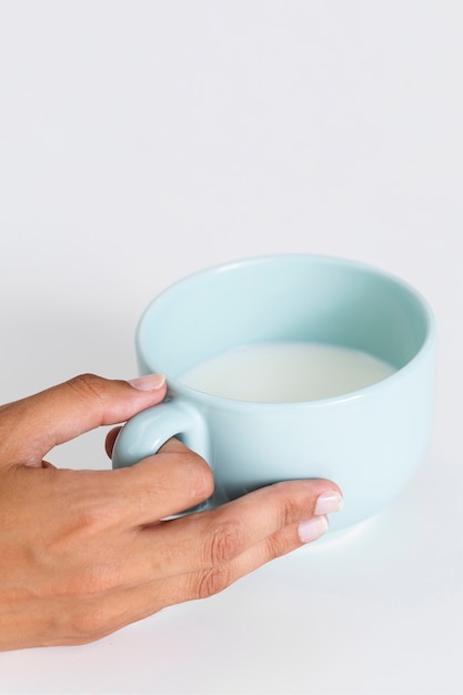 Close-up main tenant une tasse en céramique avec du lait