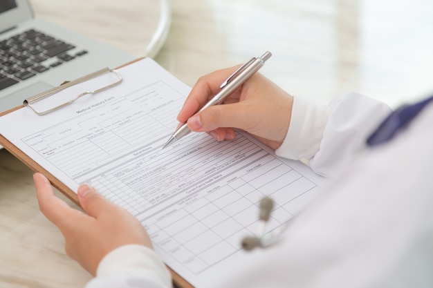 Photo gratuite close-up des mains du médecin avec presse-papiers et un stylo