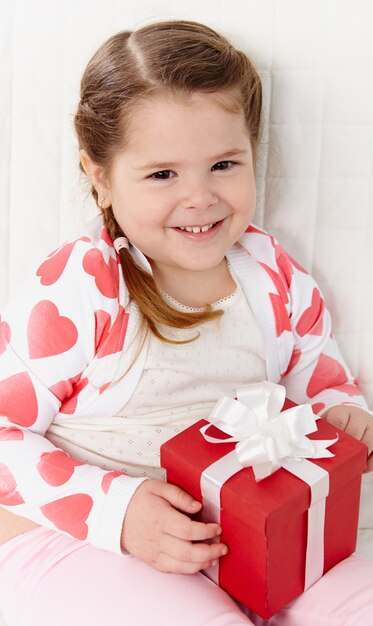 Close-up de la mignonne petite fille avec un présent rouge