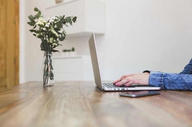 Close-up de la personne qui utilise son ordinateur portable sur une table en bois