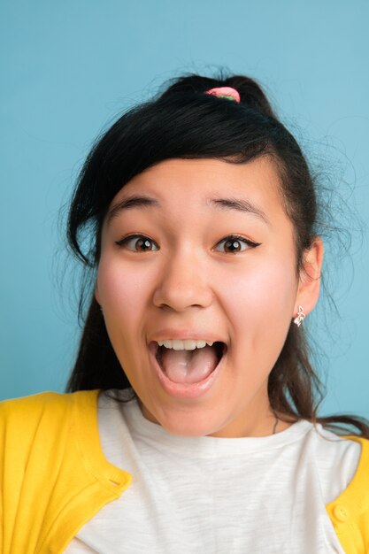 Close up portrait de l'adolescent asiatique isolé sur fond bleu studio