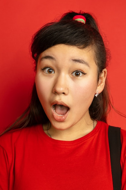 Close up portrait de l'adolescent asiatique isolé sur fond de studio rouge