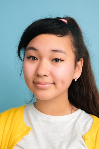 Close up portrait de l'adolescent asiatique isolé sur studio bleu