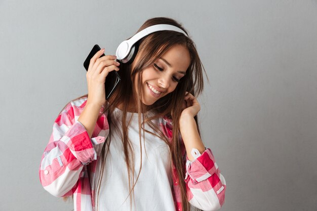 Close-up portrait of dancing young happy woman listen music with white headphones