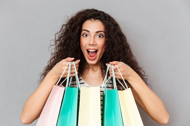 Close up portrait of female excité accro du shopping faisant du shopping être heureux et ravi d'acheter des produits préférés tenant des achats dans les mains