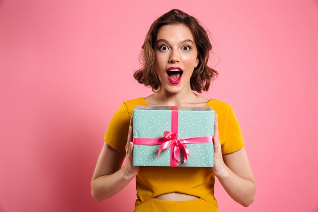 Close-up portrait of happy exited jolie brunette woman holding coffret cadeau,