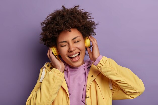 Close up portrait of happy funny femme aux cheveux bouclés écoute la musique préférée avec des écouteurs