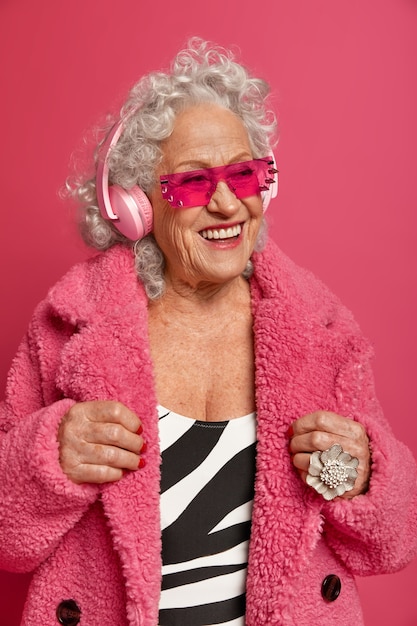 Close up portrait of happy mamie à la mode ridée portant des collants roses et manteau