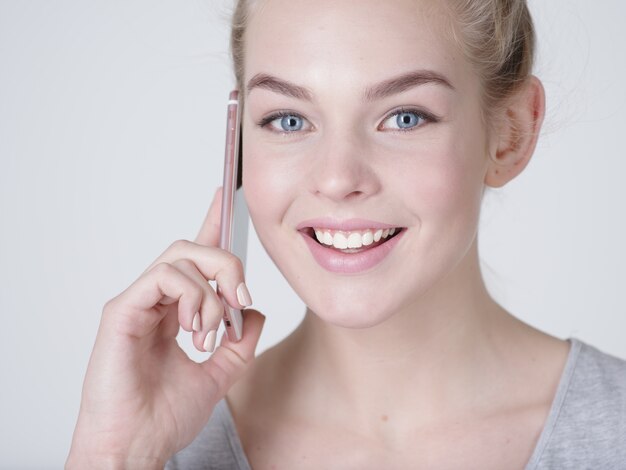 Close up portrait of a happy woman talking sur le téléphone mobile sur bacjground gris