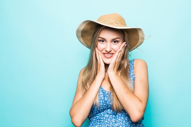 Close up portrait of a happy young woman in beach hat avec bouche ouverte regardant la caméra isolée sur fond bleu
