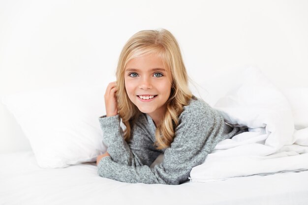 Close-up portrait of joyeuse petite fille couchée dans son lit,