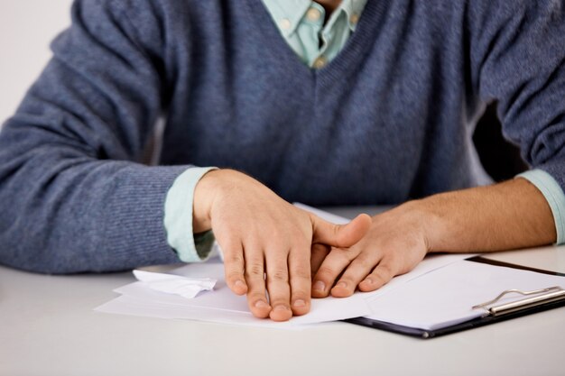 Close-up portrait of man hands, office worker make origami from documents, bored at work