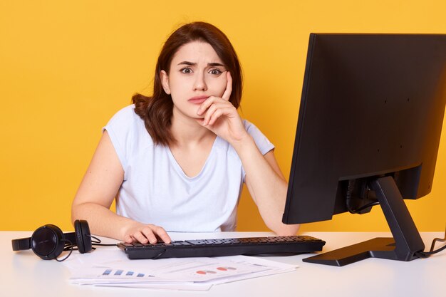 Close up portrait of pretty young female college student using desktop computer in a college library