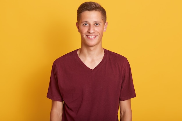 Photo gratuite close up portrait of smiling bel homme aux cheveux blonds, portant en t-shirt décontracté burgunde, debout