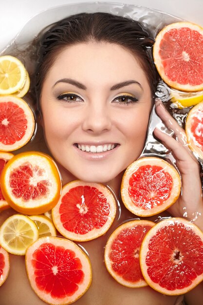 Close up portrait of smiling woman with many juteux agrumes pamplemousse citron dans la salle de bain