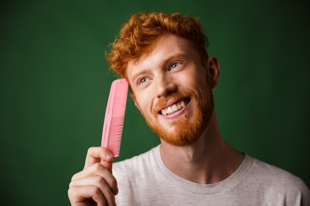 Close-up portrait of smiling young readhead beardy man with pink comb