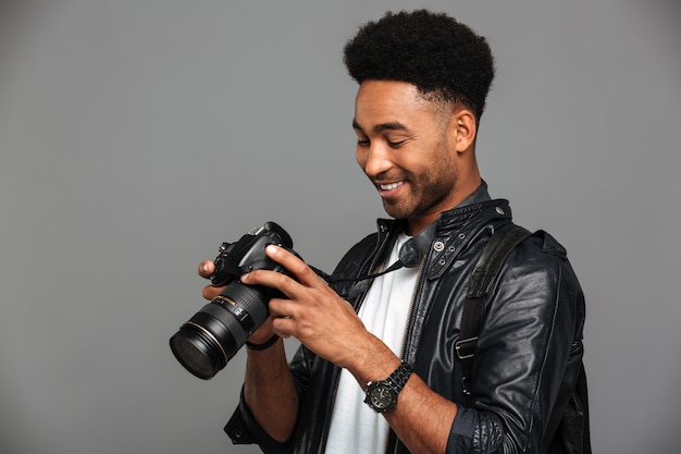 Close-up portrait of young happy afro american man holding et regardant l'écran de l'appareil photo