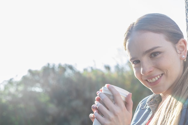 Close-up de sourire jeune fille tenant une boisson chaude