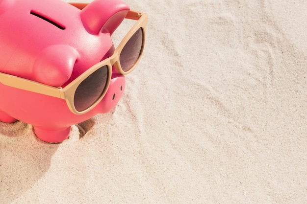 Close-up de la tirelire avec des lunettes de soleil sur le sable gardé