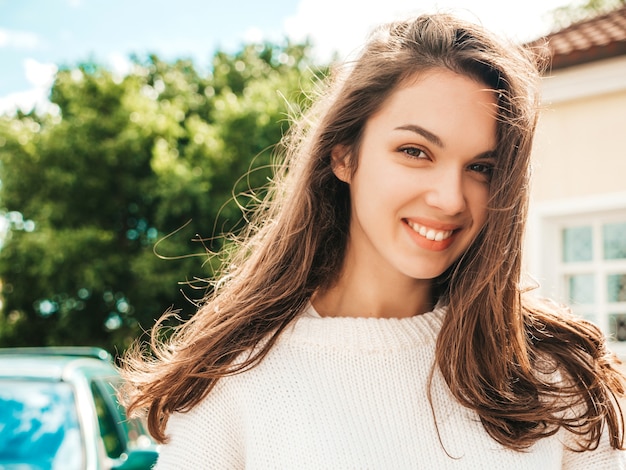 Closeup portrait de beau modèle brune souriante. Femme à la mode posant dans la rue au coucher du soleil. Jolie et joyeuse