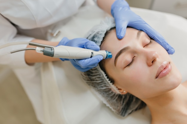 Closeup portrait de belle femme au cours de la thérapie de cosmétologie dans un salon de beauté. Procédures dermatologiques professionnelles, lifting, rajeunissement, appareils modernes, soins de santé