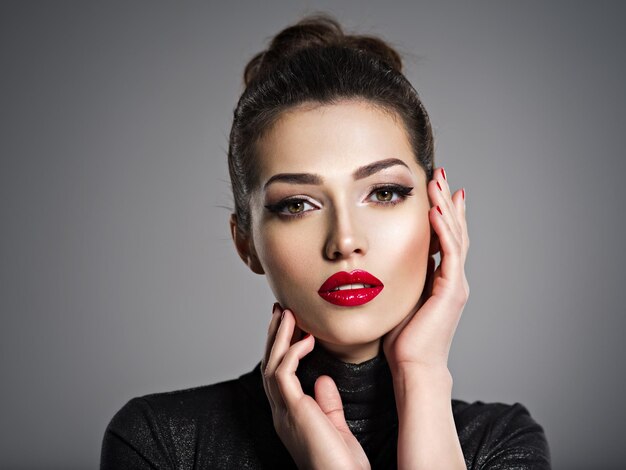 Closeup portrait de belle femme avec maquillage lumineux et ongles rouges. Sexy jeune fille adulte avec rouge à lèvres.