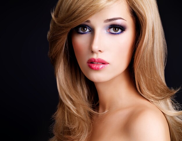 Closeup portrait d'une belle jeune femme aux longs cheveux blancs et aux lèvres rouges. Mannequin posant sur un mur noir