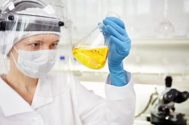 Closeup portrait female scientist holding tube conique avec solutionn liquide