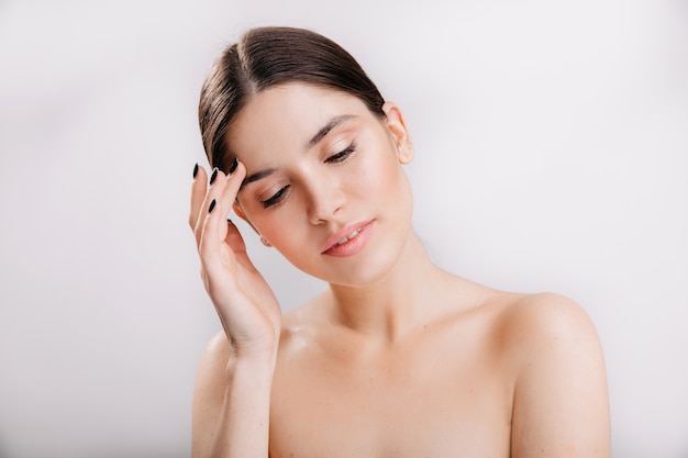 Closeup portrait de femme embarrassée avec un visage propre et beau sans maquillage sur un mur isolé.