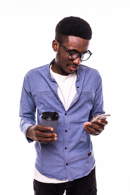 Closeup portrait happy smiling man reading good news on smart phone holding mobile, drink cup coffee isolated white white wall. Expression du visage humain, émotion, dirigeant d'entreprise