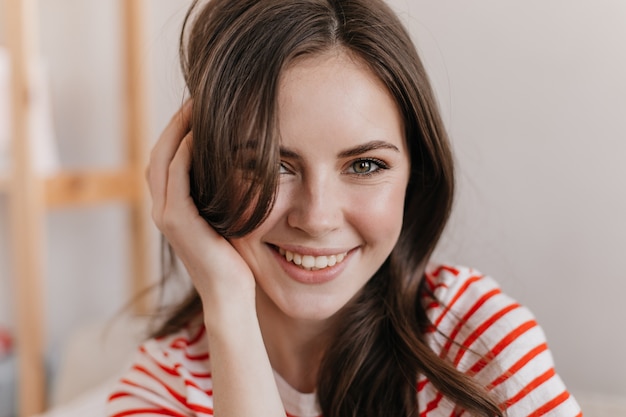 Closeup portrait de jeune femme aux yeux verts touchant ses cheveux et regardant vers l'avant