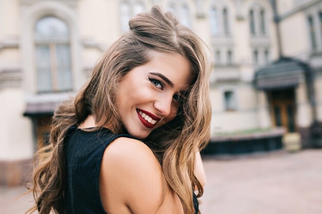 Closeup portrait de jolie fille aux longs cheveux bouclés souriant