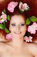 Photo gratuite closeup portrait of beautiful smiling redhead ginger woman face avec des fleurs colorées dans les cheveux