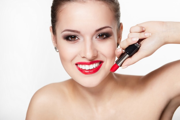 Closeup portrait of sexy smiling caucasian young woman model with glamour red lips, bright makeup, eye arrow makeup, purity teintion with red lipstick. Une peau parfaitement propre, des dents blanches